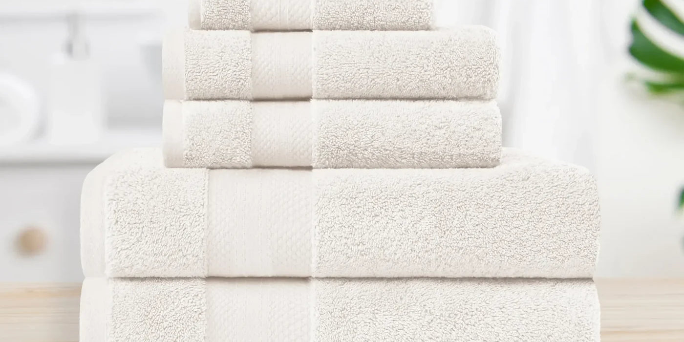 Superior Aria 800 GSM cotton bath towel set in ivory, folded in a bathroom