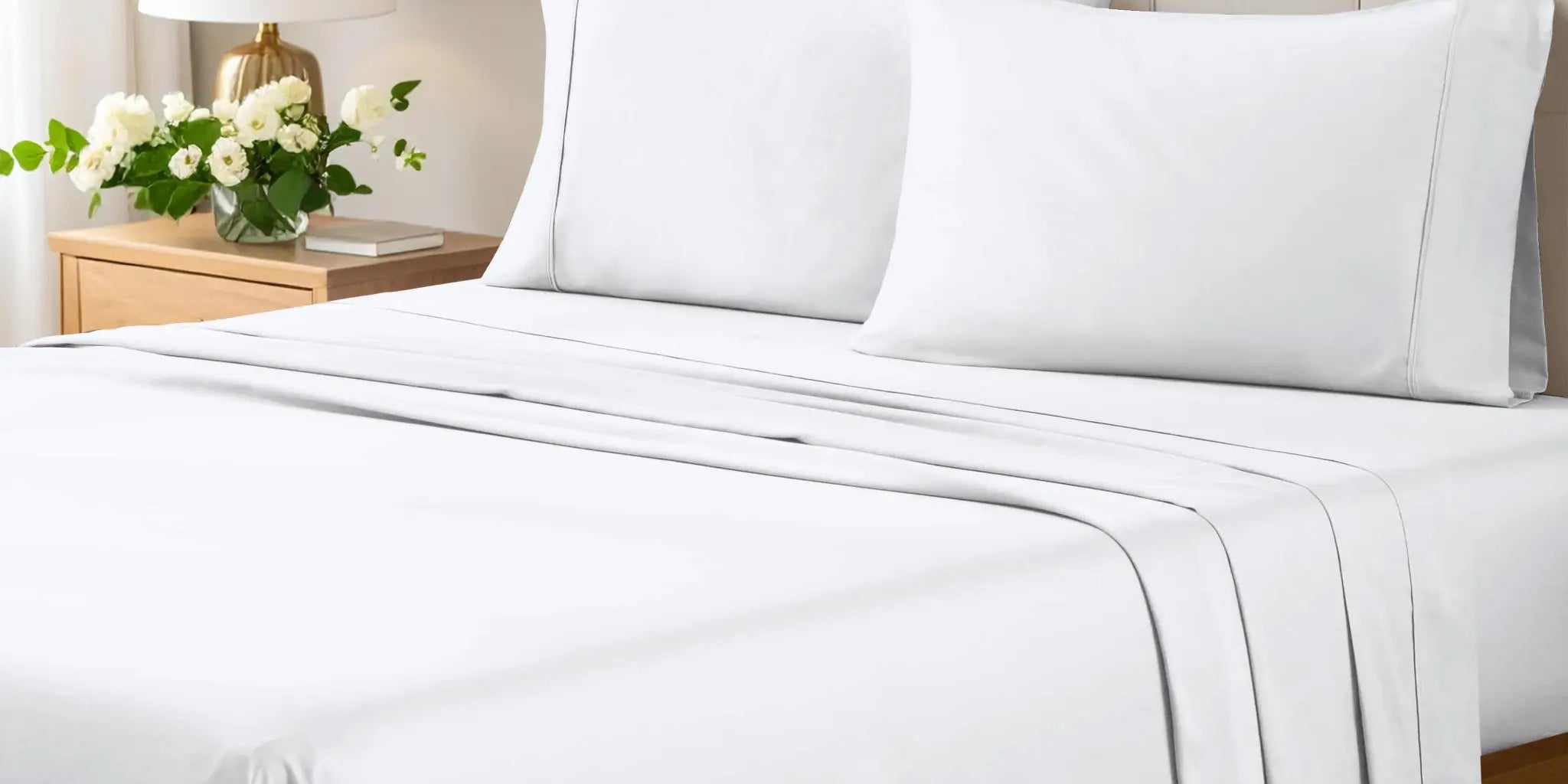 Superior white cotton sheet set on a made bed with an upholstered headboard