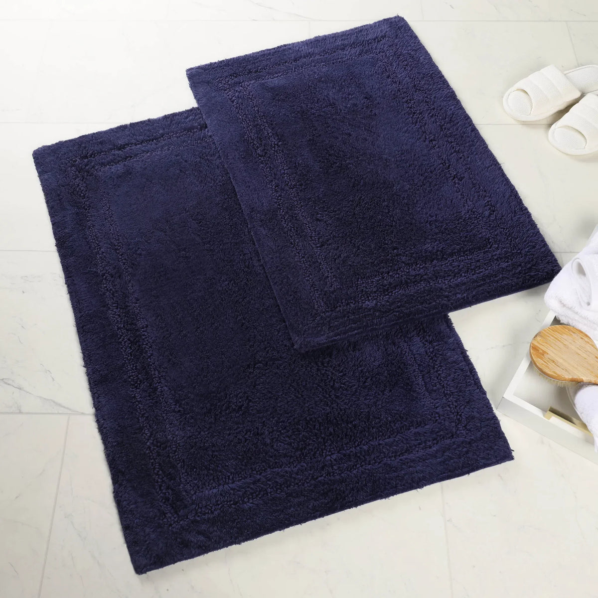 Superior navy cotton bath rug set on a marble bathroom floor with slippers and a bath brush